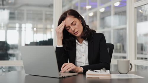 Stressed Businesswoman with Headache at Work in Office