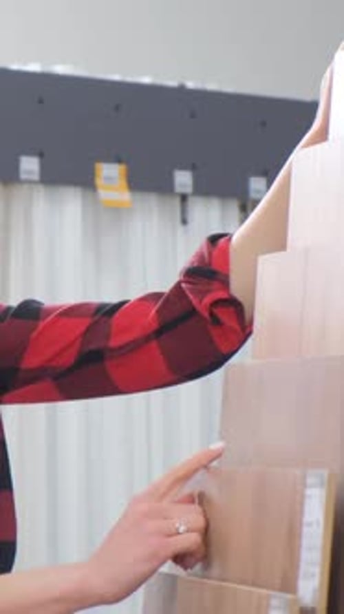 Woman Inspecting Wood Flooring Samples in Store