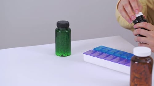 Person Sorting Pills on White Table