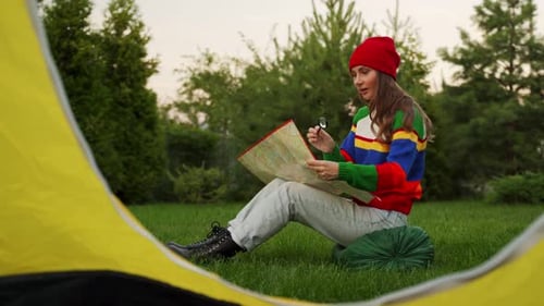 Young Woman Studies Map in Tent in Countryside