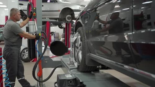 Auto Mechanic Aligns Car Wheel with High Precision Equipment at Vehicle Service Center Expert