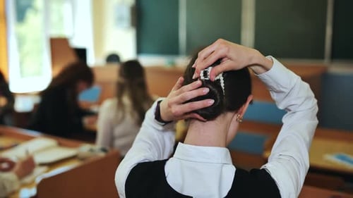 Teen Student Adjusts Hair in Classroom Setting