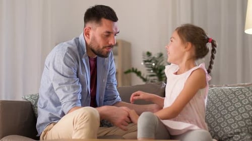 Father Tickles Daughter on Couch in Living Room
