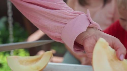 Les enfants partagent des fruits Les enfants reçoivent des tranches d'une femme souriante Une femme avide offre des tranches de melon à