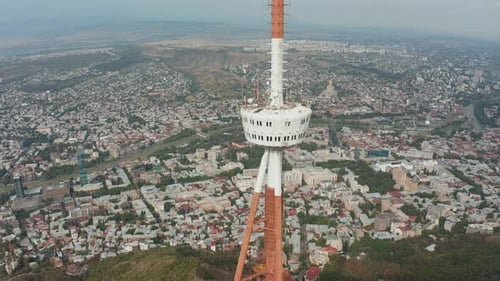 Rotating aerial view of Tbilisi TV tower in Mtatsminda park. Pan to left. City of Tbilisi in the bac
