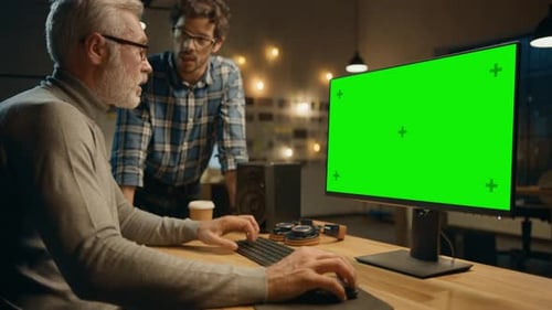 Am Abend arbeitet ein kreativer Mann mittleren Alters an einem Desktop-Computer, grüner Mock-up, Has Conve