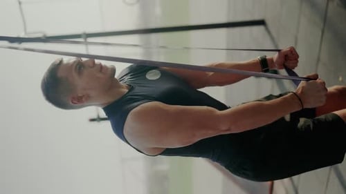 Junger Mann im Fitnessstudio führt Widerstandsbandübungen durch