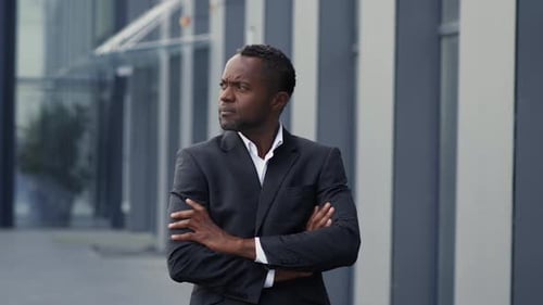 Confident Middle Aged African American Businessman with Folded Arms Posing Outdoors Near Office