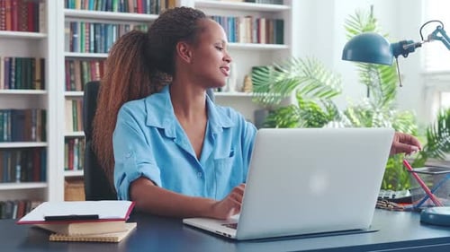 Woman Working at Desk with Laptop and Books