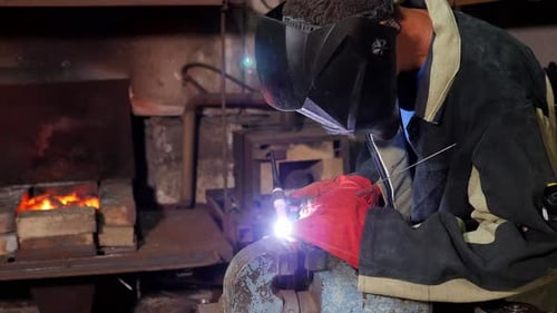 A Handyman Performs Welding and Grinding at His Workplace in the Workshop