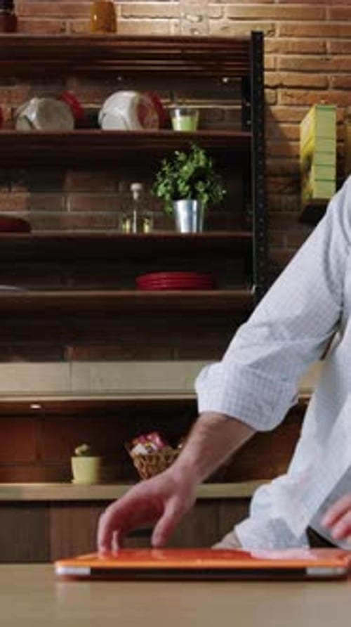 Man Opens Laptop in Kitchen, Celebrates Success