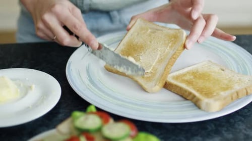 Close-up of a Woman Spreading Butter on Her Toast.