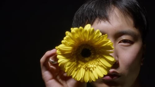 Young Adult Holding Bright Yellow Gerbera Daisy