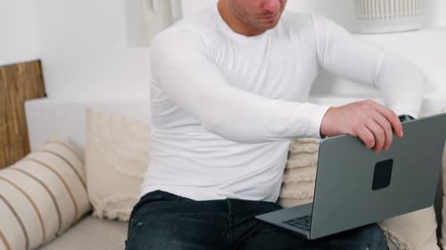 Caucasian male wearing white shirt opens his laptop. Working from home remote from office.