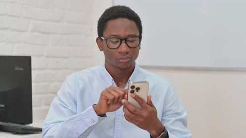 Young Adult Using Smartphone at Computer