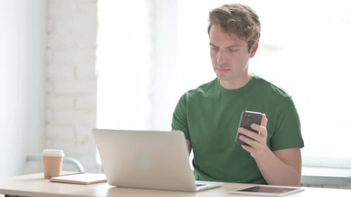 Young Adult Using Phone at Desk