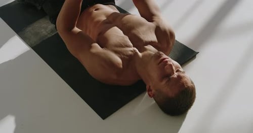 Athletic Young Man Training Abs on Mat in Studio Setting