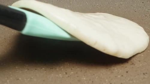 I turn the pancake over in a frying pan, with a silicone spatula. extreme close-up.