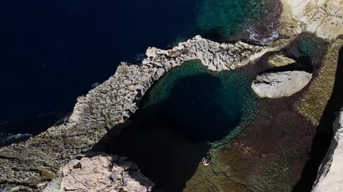 Drone aerial view over Dwejra Hole in Gozo, Malta, showing divers in clear waters, cinematic 60FPS