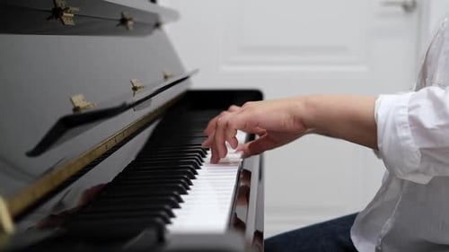 Hands playing a black piano in a home