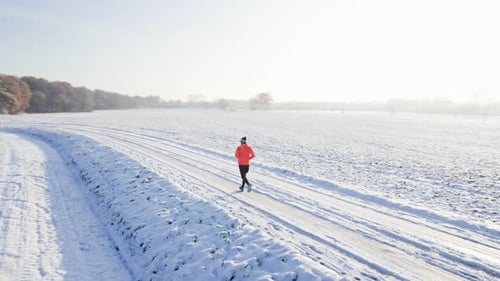 Male Runner Jogging on Winter Snowy Road