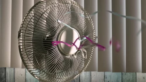 Truck shot from left to right of a rotating fan with colorful ribbons on the grill, in the backgroun