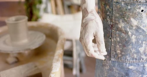 Main sale d'un potier biracial, debout dans un studio de poterie, Ralenti