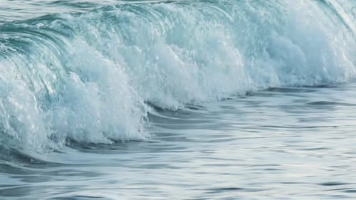 Slow motion of beautiful blue sea water waves splashing against tropical sand beach. Pan shot.