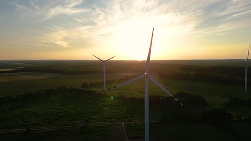 Silhouette of a windmill in the sun. Aerial close up shot of wind mills rotating by the force of the
