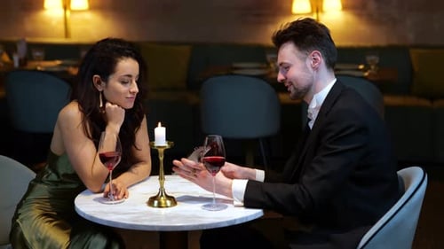 Happy Man Showing Smartphone for His Girlfriend While Having Romantic Date in the Restaurant
