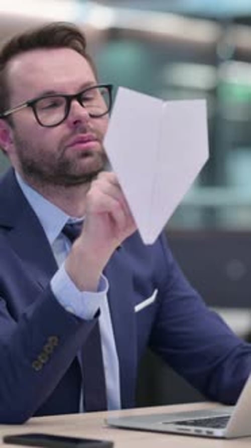 Vertikales Video eines Geschäftsmannes, der ein Papierflugzeug im Büro hält