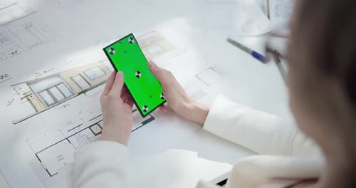 Hands Using Chroma Key Phone Over House Plans