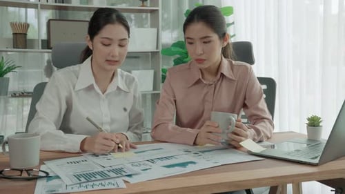 Deux jeunes femmes d'affaires enthousiastes travaillant ensemble dans le bureau