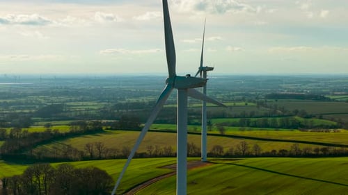 Windmill Turbines Spinning Generating Renewable Electricity Over Expansive Green Landscape