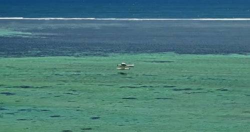 Luftaufnahme eines Wasserflugzeugs, das auf kristallklarem Wasser startet oder landet, Mauritius