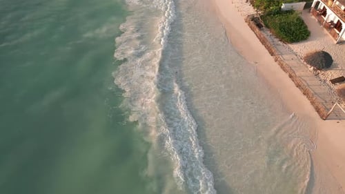 Aerial view of gentle waves lapping a sandy beach. Zanzibar, Tanzania.