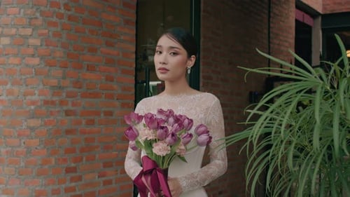 Portrait of Charming Thai Bride in Lace Wedding Dress Posing on the Street Holding Wedding Bouquet