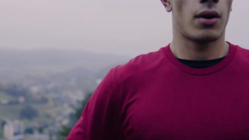 Young runner breathes deeply resting after jogging on hilly meadow in autumn nature