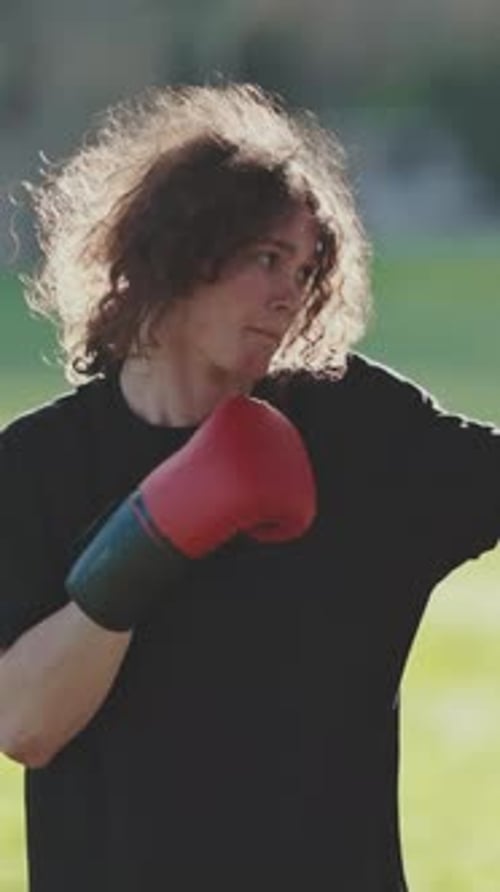 Young Man Boxing with Red Gloves in a Park