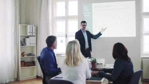 Businessman delivers dynamic presentation to diverse colleagues in modern office