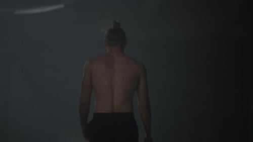 Athletic man walking in dark loft building after cardio workout in gym