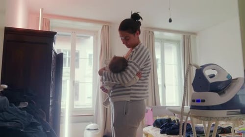 Woman Holding Infant in Bedroom Interior Daytime
