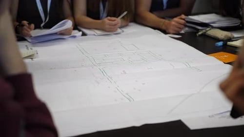 Civil engineers sitting around technical layout drawing at construction site