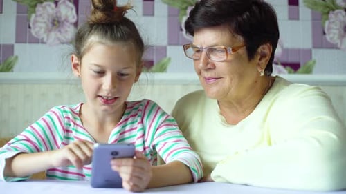 Child and Grandmother Looking at Smartphone Together