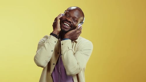 A Man Joyfully Enjoys Music with Headphones in a Bright Setting
