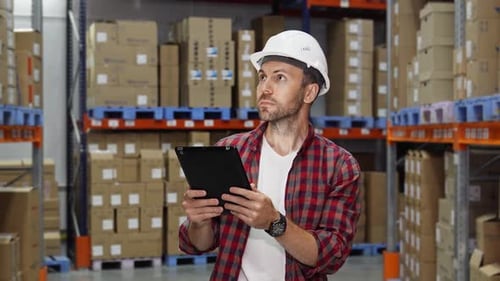 Warehouse Worker Conducts Inventory Check While Reviewing Data on Tablet