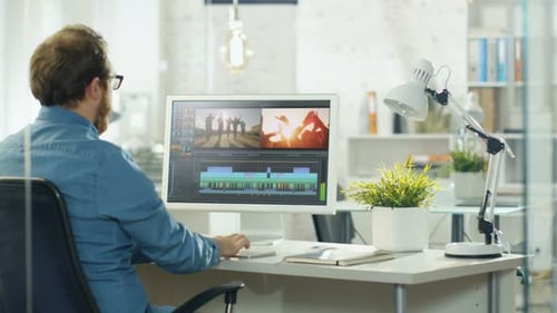 Male Video Editor Works with Footage and Sound on His Personal Computer with Two Displays. He Works