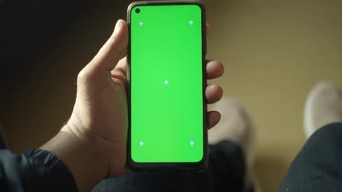 Pov of Young Man Hand Using Smart Phone with Green Screen Sitting on a Chair
