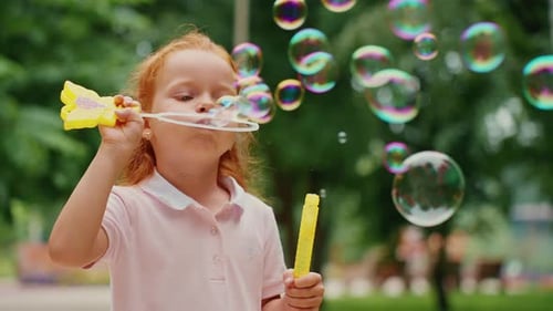 Young Girl Blowing Bubbles in a Sunny Park on a Warm Summer Day