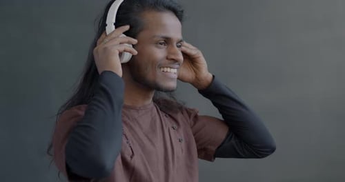 Young Adult Puts on White Wireless Headphones and Smiles